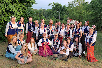 Die SängerInnnen von Kariolle mit osteuropäischen Kleidung stehen zusammen in der Natur.