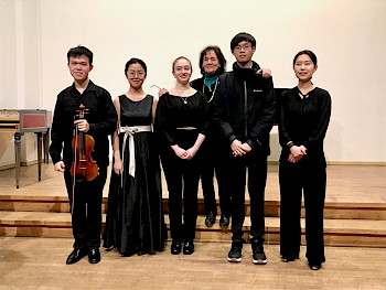 5 junge Musiker in einem Saal, einer hält eine Geige