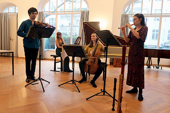 4 Musiker mit Barockinstrumenten musizieren auf einer Bühne