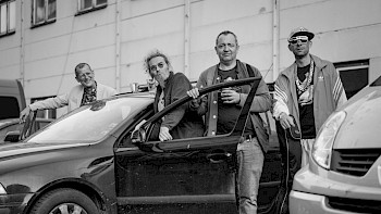 Schwarz-Weiß-Bild: 4 Männer neben einem Auto