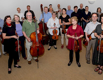 Ein Senior-Synphonie: Alle MusikerInnen haben entweder Geigen/Cello. Sie schauen und lachen in dem Kamera zusammen