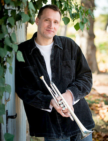Joachim Schäfer lehnt mit seiner Trompete an einer Tür.