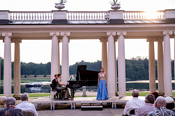Eine Sängerin bei einem Auftritt in Begleitung von zwei Pianisten unter freiem Himmel