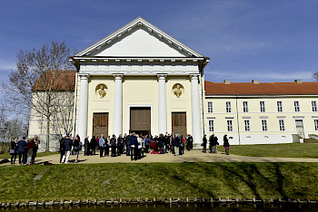 Zeigt das Schlosstheater Rheinsberg mit einer Ansammlung von Menschen davor