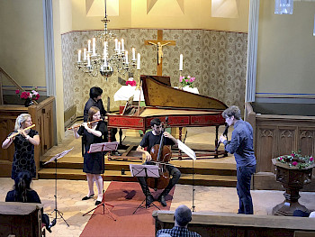Studierende der «Alte Musik» UDK-Berlin bei einem Auftritt in einer Kirche. Im Vordergrund sieht man von rechts nach links einen Flötisten, einen Cellonisten und zwei Flötistinnen.