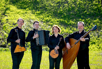 Exprompt, zeigt die vier Musiker*innen mit ihren Instrumente vor einer grünen Wiese.