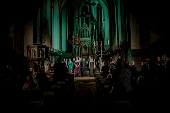 Die SängerInnen singen in der Kirche, unter blauen Licht