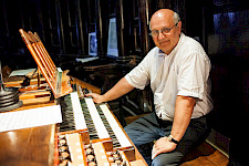 Ein Mann mit Brille: Er sitzt vor dem Orgel