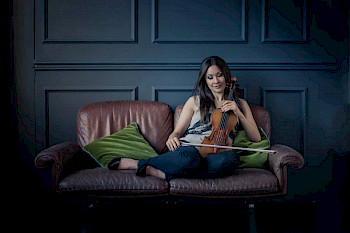 Eine Frau mit Violine auf einem Sofa