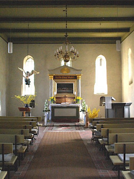 Bild zeigt das innere einer Kirche, die Frontalansicht eines Altars, mit leeren Bänken davor