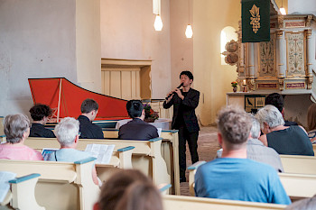 Ein Flötist und ein Cemballist spielen in einer Kirche