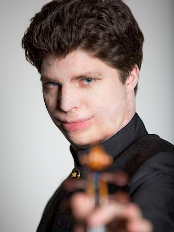 Junger Mann mit Brandwunden um Gesicht und Violine
