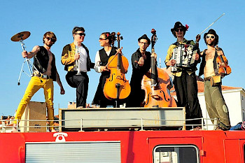 Ein Musikband mit 6 MitgliederInnen, sie haben verschiedenen Musikinstrumente im Hand