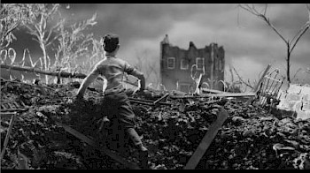 Ein Mann steht in einem Schwarzweißbild vor einer Ruine