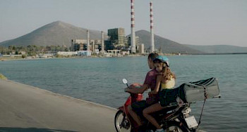 Zwei Menschen auf einem Motorrad fahren eine Küste entlang