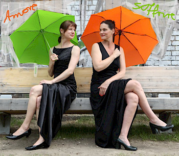 2 Frauen in schwarzen Kleiden mit den bunten Schirmen