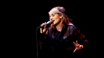 Eine Sängerin singt vor dem schwarzen Hintergrund