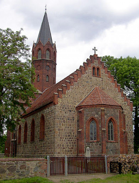 Bild zeigt eine Kirche von schräg vorne, mit einem Kirchturm