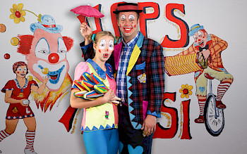Clown Hops und Hopsi stehen bunt vor dem Kamera.