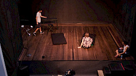 3 Personen üben ein Theaterstück auf der Bühne.