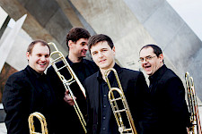 4 Musiker von Trombquartet mit Pauke und Trompete im Händen