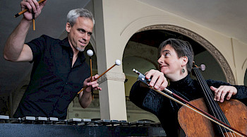 Ein Mann spielt Vibrophon und eine Frau Cello. Sie schauen sich dabei an.