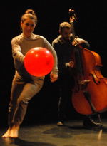 Eine Frau spielt mit einem roten Luftballon. Ein Mann spielt Cello