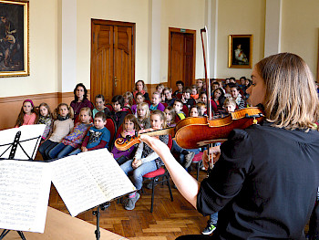 Eine Frau spielt Violine vor Kindern in einem Konzertsaal