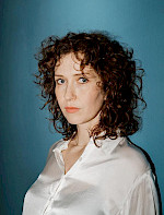 Eine Frau mit lockeren Haaren vor dem blauen Hintergrund