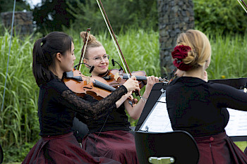 3 Frauen spielen unter freiem Himmel auf Geigen