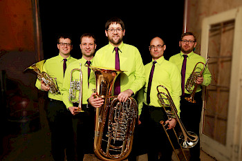 Fünf Musiker mit Blechblasinstrumenten und grünen Hemden