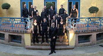Mehrere Musiker in schwarzer Kleidung stehen auf einer Freitreppe