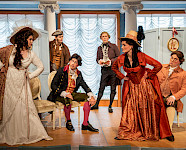 Schauspielerinnen und Schauspieler in historischen Kostümen stellen ihre Rolle in einem klassischen Stück dar.