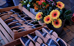 Holzpantinen in einer Kiste, dahinter Blumen