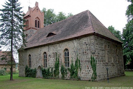 Graue Kirche, die teilweise mit Efeu bewachsen ist, mit Backstein Kirchturm