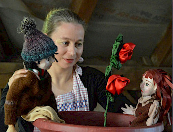 Eine Frau hält zwei Marionetten