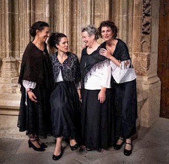 4 Frauen in Folklorekleidung stehen vor einer alten Kirche
