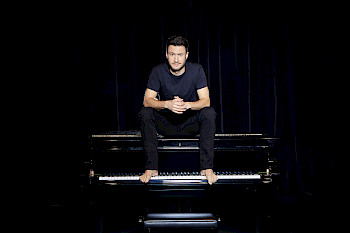 Ein Mann sitzt auf einem Piano
