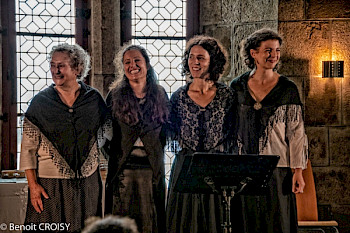 4 Frauen in folkloristischen Kleidern in einem mittelalterlichen Saal