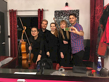 5 junge Musiker in einem Umkleideraum fotografieren sich selbst mit Handy im Spiegel