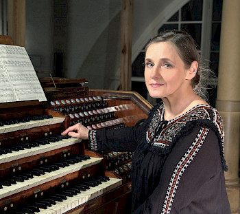Eine Frau in Folklorekleid sitzt an einer Orgel