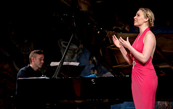 Eine Frau in rotem Kleid mit Pianist auf einer Bühne