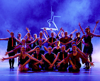 Eine Gruppe Tänzerinnen posiert auf einer blau beleuchteten Bühne
