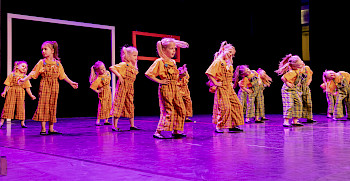 Kinder tanzen in karierten Kostümen auf der Bühne
