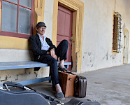 Mann mit Basecap und Koffern auf einer Bank sitzend
