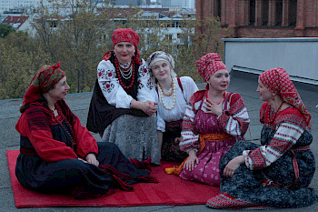 auf dem Boden sitzende Frauen in folkloristischer Kleidung