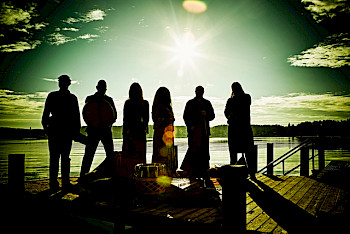 6 MusikerInnen sehen in die Sonne. Sie wurden von den Rücken photographiert