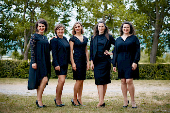 5 Musikerinnen in schwarzen edlen Kleidern posieren in einem schönen Garten