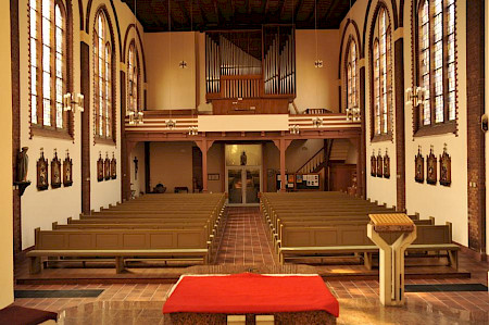 In einer Kirche mit Blick auf leere Bänke und eine Orgel, die über dem Ausgang ist