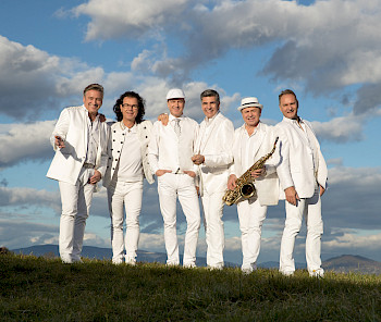 6 Männer stehen auf der Wiese mit weißen Anzügen
